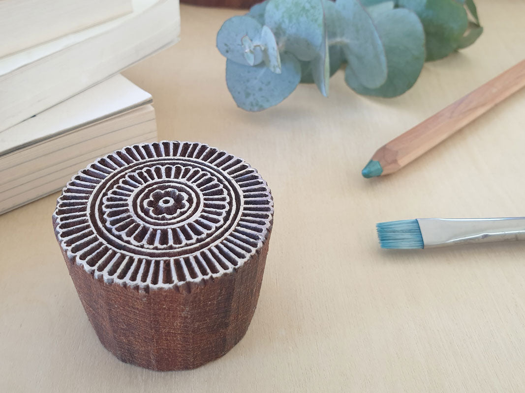 Round wood block printing stamp with flower in middle.